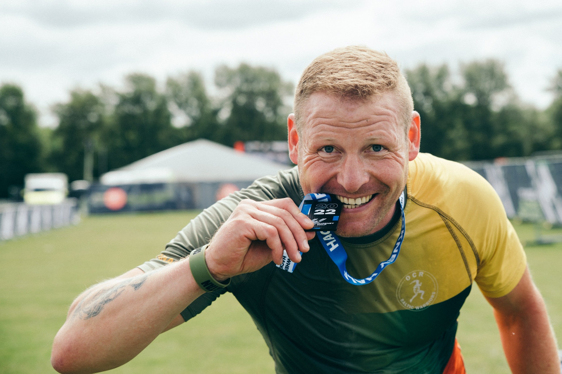 a men biting hackney marathon medal